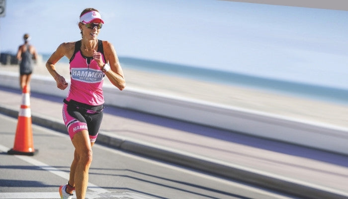 Female Hammer Athlete Running In Pink Hammer Kit next to beach